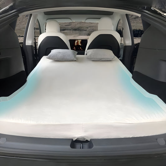 a white Mattress made for tesla model y by Clevisco placed behind the front passenger seat and driver seat along with two grey pillows